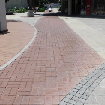In the foreground Corobrik’s Burgundy pavers have been laid in a basket weave pattern with grey cobbles edging the Burgundy pavers and forming a border with the light Cederberg pavers